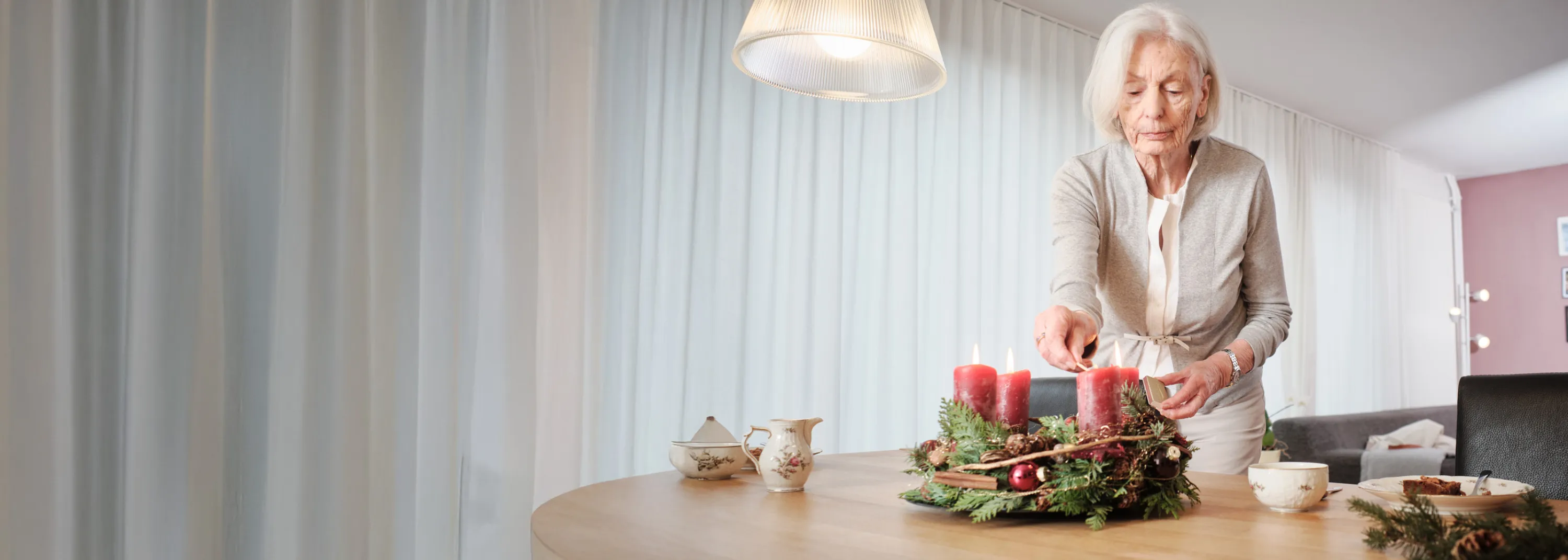 Dame âgée allume les bougies de la couronne de l’Avent.