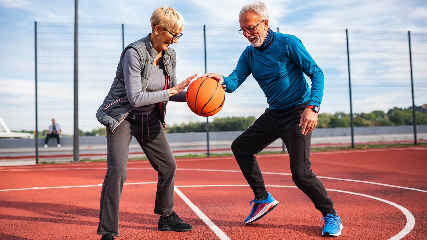 Ein älteres Paar spielt Basketball.